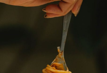 Culinary Tours - Crop faceless female using fork while eating yummy spaghetti alla bolognese during dinner in restaurant