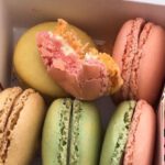 Dessert Spots - From above of cardboard container filled with delicious colorful macaroons placed on pink surface with black details