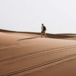 Hiking Trails - A person walking across a desert with a camel